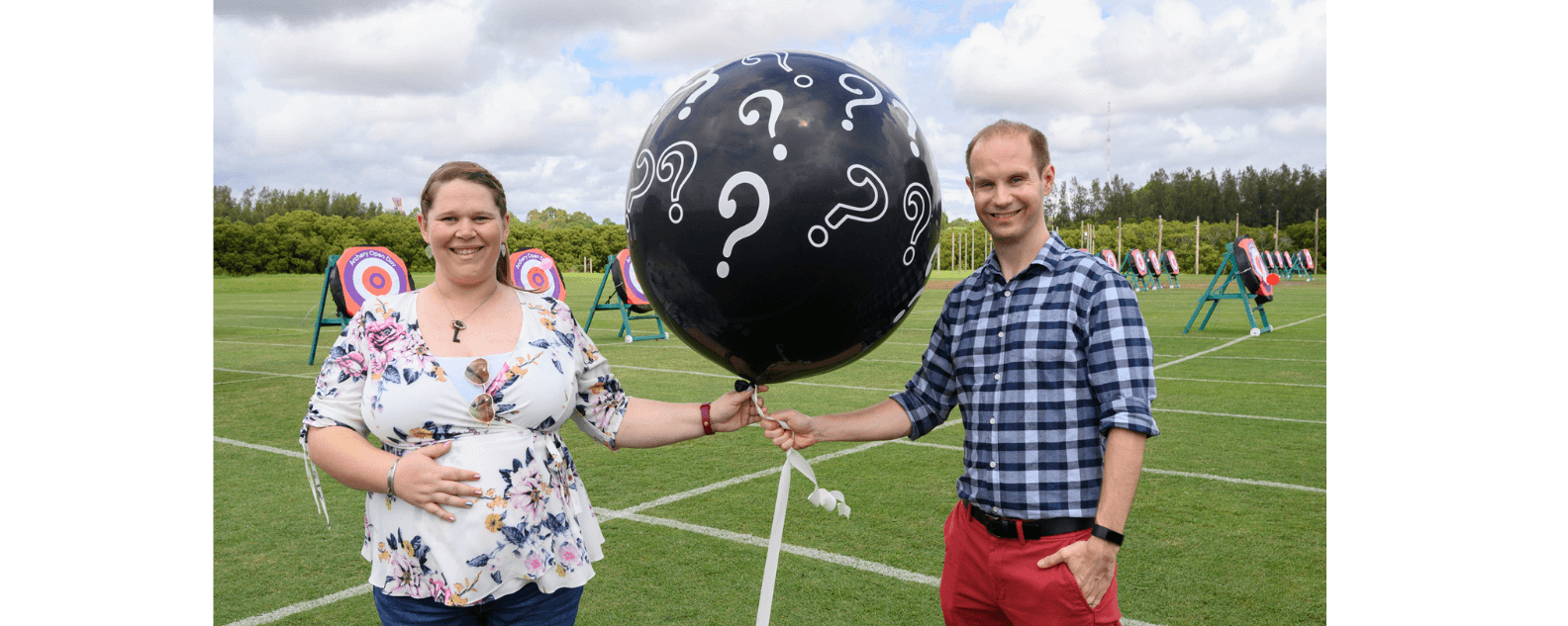 Couple holding black balloon with question marks